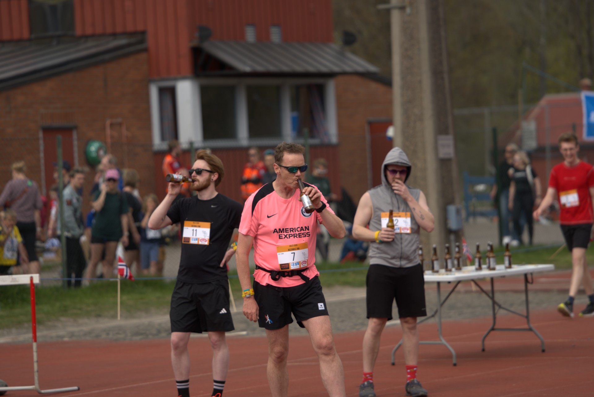 Tre løpere ved ølstasjonen, én med rosa startnummer 7 drikker