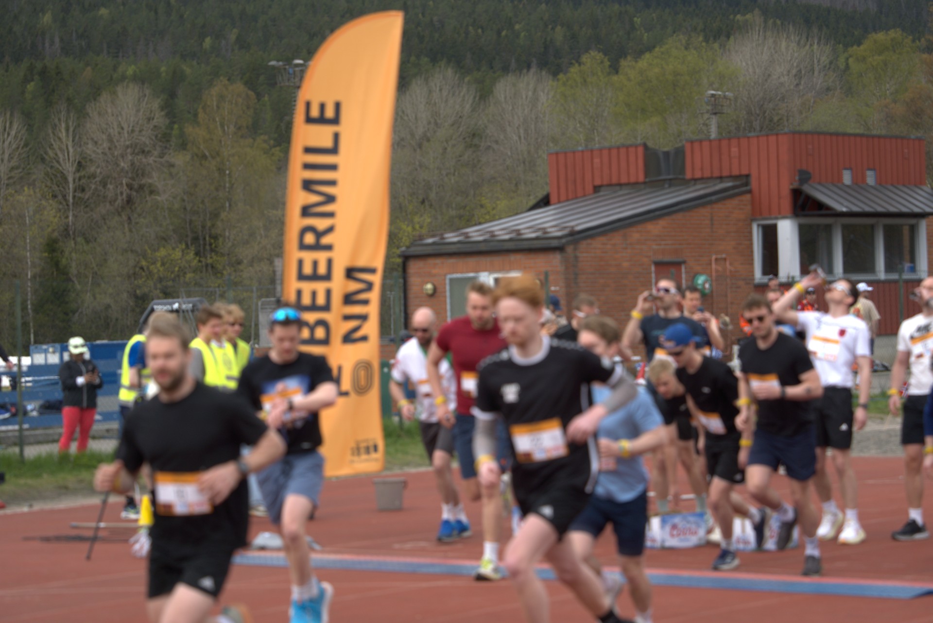 Deltakere tar sats fra startstreken under NM i Beermile, med BEERMILE NM-beachflagg i bakgrunnen